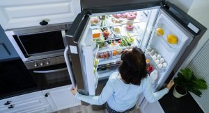 Frau öffnet einen Side-by-Side-Kühlschrank