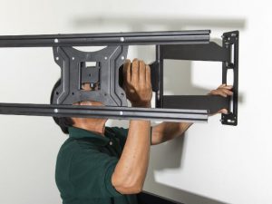 Mann montiert TV-Halterung an Wand