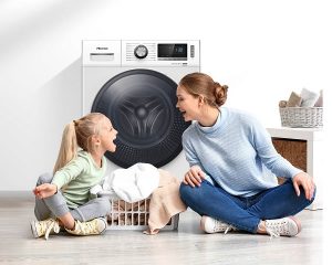 Frau und Tochter räumen lachend Waschmaschine aus